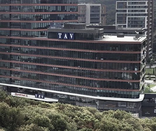 TAV Holding Türkiye merkezli küresel havalimanı işletmeciliği şirketleri arasında yer alan TAV Havalimanları Holding, havalimanı işletmeciliği, terminal hizmetleri, yer hizmetleri, duty free, yiyecek-içecek, bilişim ve güvenlik alanlarında faaliyet gösteren çok sektörlü yapısıyla dikkat çekiyor. 1997 yılında kurulan şirket, bugün Avrupa, Orta Doğu, Afrika ve Orta Asya’da faaliyet gösteren önemli havalimanı işletmecileri arasında yer alıyor. Özellikle uluslararası operasyon kapasitesi ve hizmet çeşitliliğiyle öne çıkan TAV Havalimanları Holding, Türkiye’nin küresel ölçekte marka değeri oluşturan şirketlerinden biri olarak değerlendiriliyor. Konulu bir haber görseli.