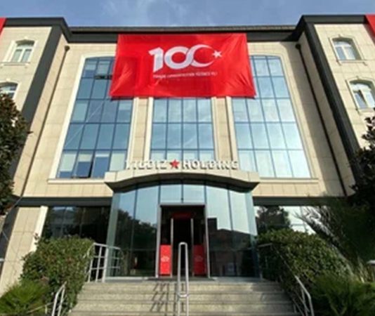 Yıldız Holding Türkiye’nin en büyük şirket topluluklarından biri olan Yıldız Holding, gıda, perakende, hızlı tüketim ürünleri, ambalaj ve e-ticaret alanlarında faaliyet gösteren çok sektörlü yapısıyla dikkat çekiyor. Temelleri 1944 yılında Sabri Ülker ve Asım Ülker kardeşlerin İstanbul’da küçük bir bisküvi üretim atölyesi kurmasıyla atılan grup, bugün dünyanın farklı bölgelerinde faaliyet gösteren küresel bir organizasyona dönüşmüş durumda. Özellikle atıştırmalık ürünler ve perakende sektöründeki güçlü markalarıyla öne çıkan Yıldız Holding, Türkiye’nin uluslararası ölçekte en güçlü şirketlerinden biri olarak değerlendiriliyor. Konulu bir haber görseli.